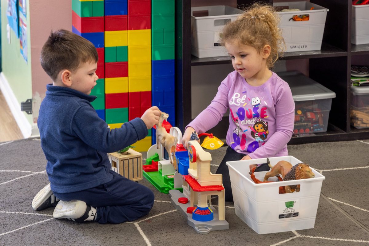 Children playing with animal figures and blocks in a Chatter Splatter classroom